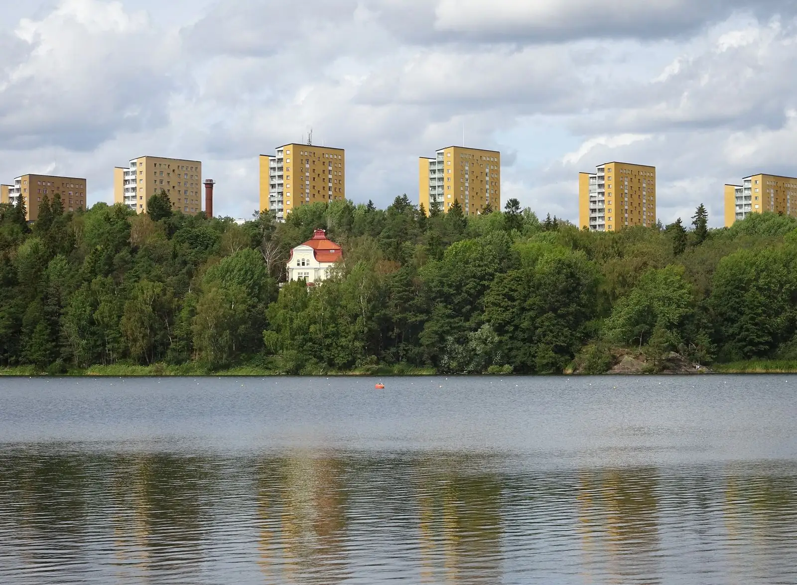 Sjön Magelungen en sommardag med Farstas bostadshus vid stranden