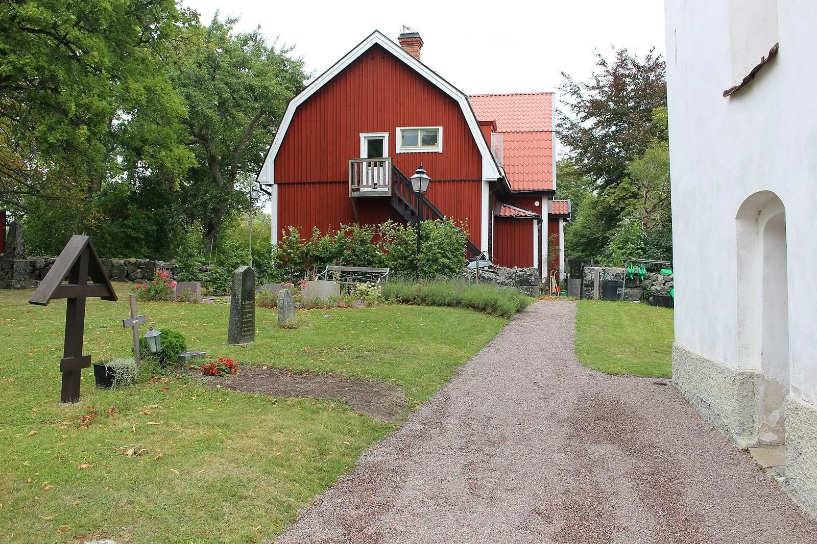 Röd byggnad vid Alsike kyrka och kloster en sensommardag