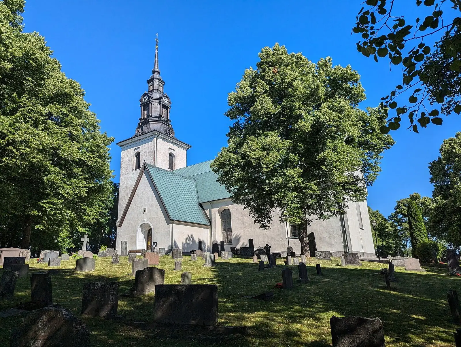 Västerlövsta vita kyrka bland gröna lövträd