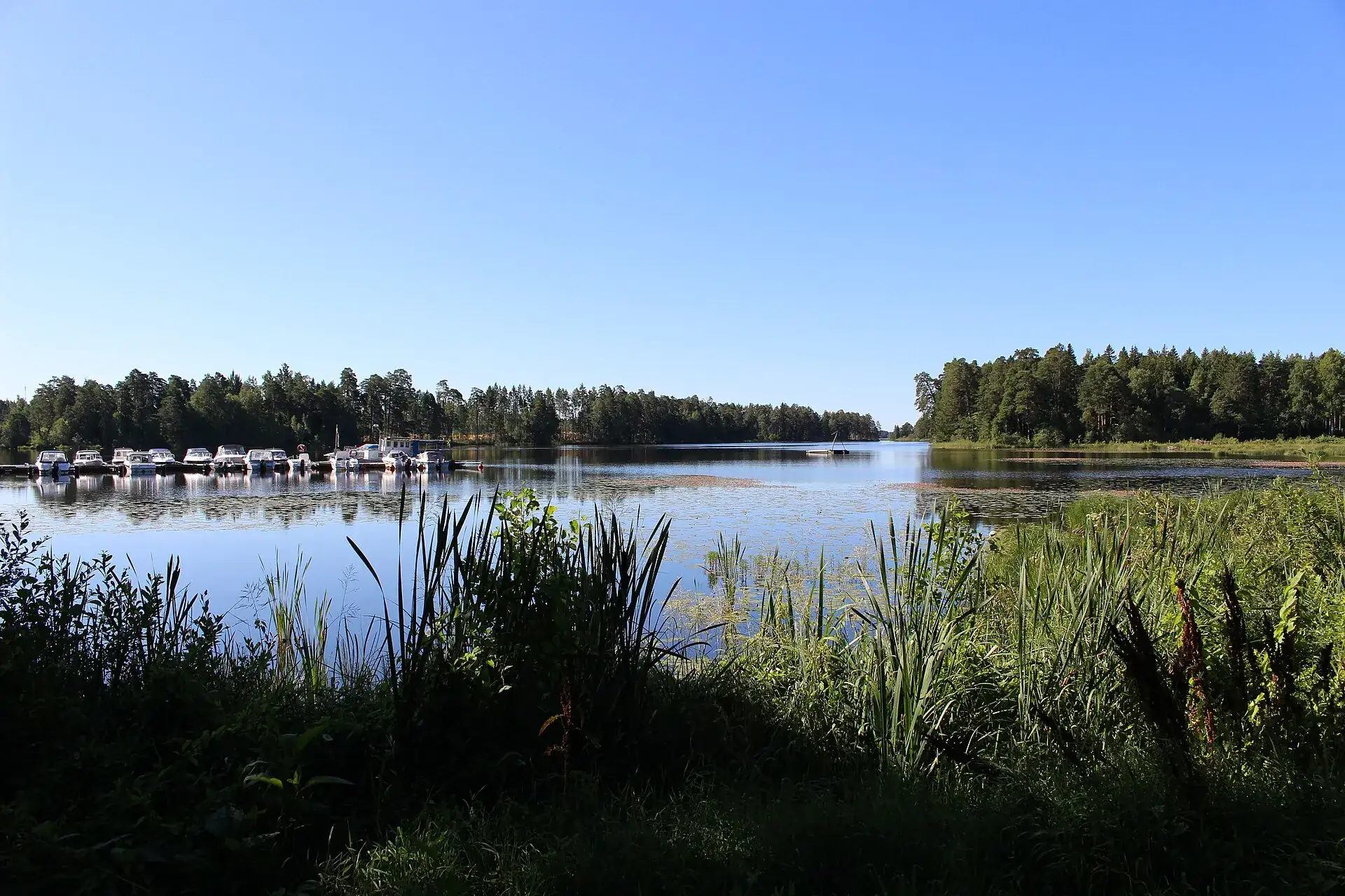 Dalälven vid Söderfors en klar sommardag, med båtar vid en brygga