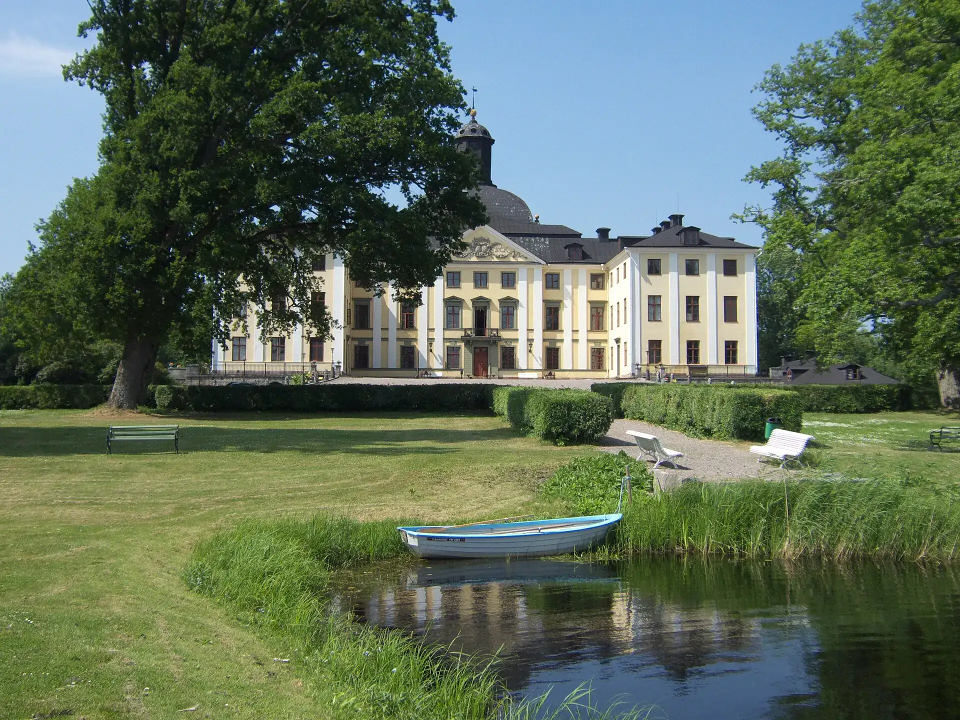 Örbyhus slott bakom parken, med en roddbåt vid vattnet i förgrunden