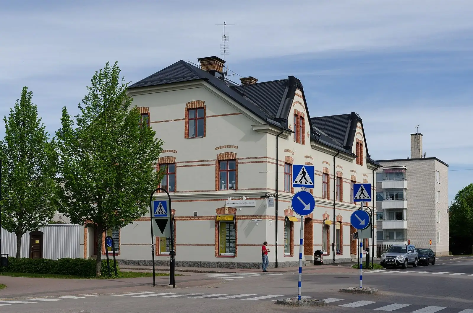 Gatukorsning i centrala Tierp med ett ljust tvåvåningshus med röda tegeldetaljer