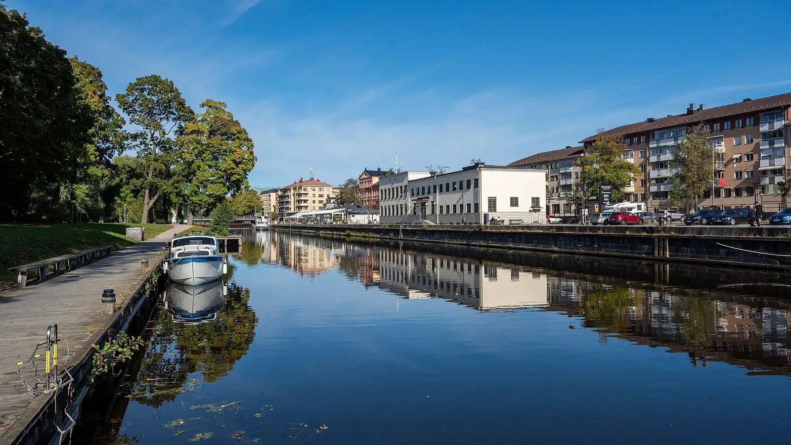 Fyrisån genom centrala Uppsala en sensommardag, med hus som speglar sig i vattnet