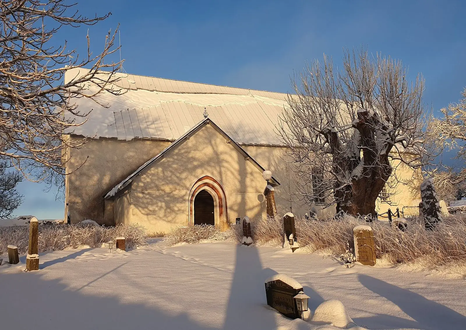 Litslena medeltida kyrka i snö och vintersol