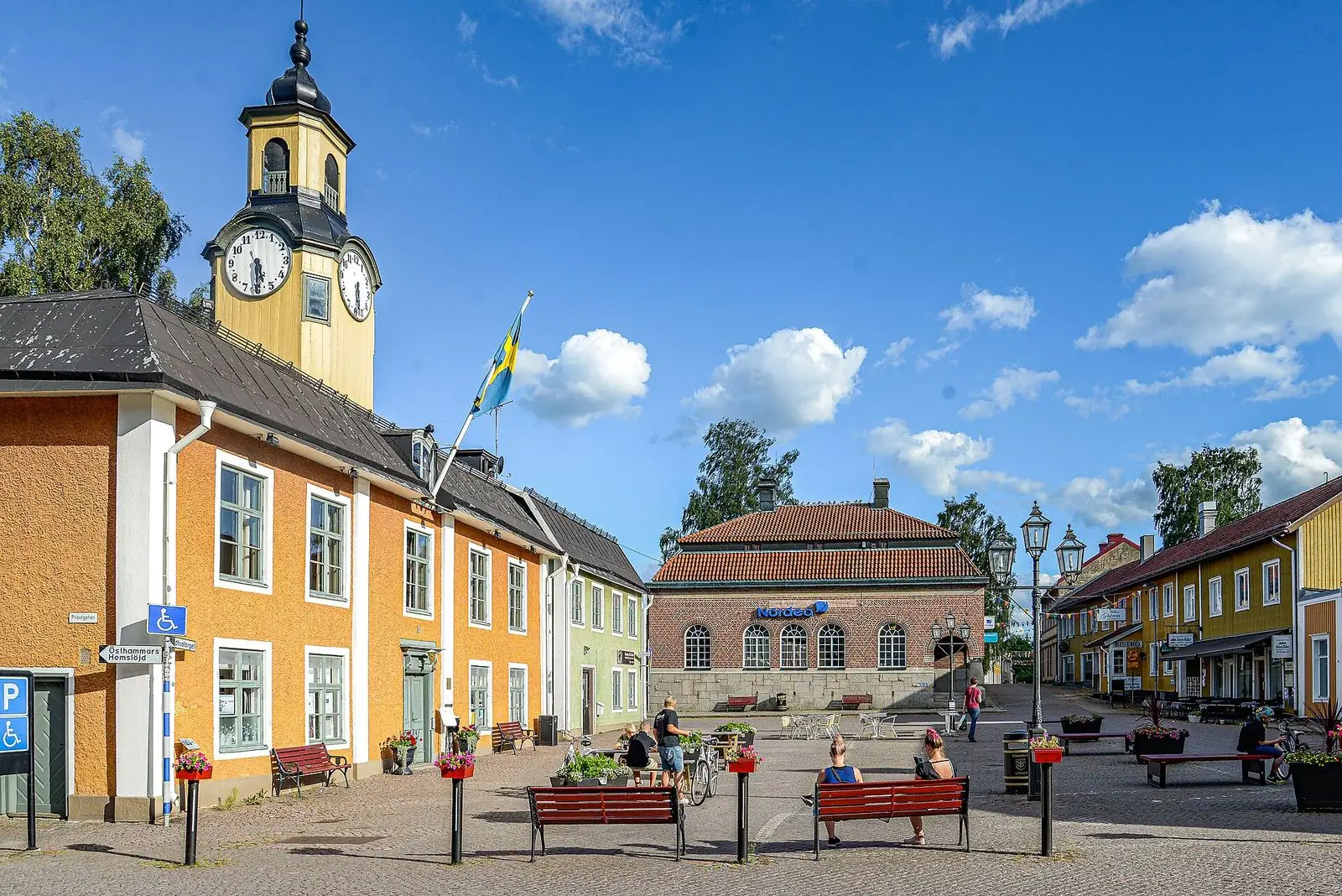 Gula hus med klocktorn vid ett torg i Östhammar en sommardag