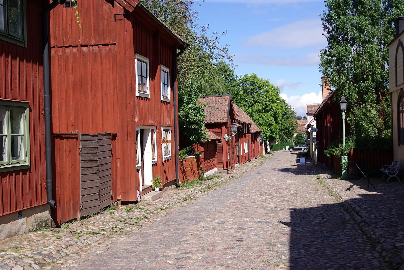 Röda trähus längs en kullerstensgata i Gamla Linköping